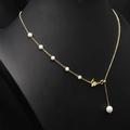 Collier de perles dorées élégant avec pendentif nœud sur un présentoir mannequin noir - Collier Asymétrique Ajustable