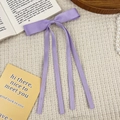 Detailed close-up of lavender satin ribbon bow hair clip with long flowing streamers - Purple