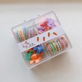 Detail of candy-colored elastic hair ties and mini clips in a transparent four-grid box - Mickey