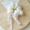Detailansicht eines weißen Spitzen-Scrunchies mit langen Quastenbändern und Stickerei - Spitzenkante Scrunchie / Weiß