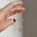 Detail of a gold choker necklace with small round charms held by a hand - Disc
