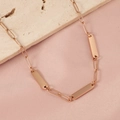 Detail shot of rose gold bar pendant and paperclip chain on beige stone and silk - Rose Gold + 3 Accessories
