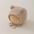 Detailed close-up of baby knit earflap hat with dual pom-poms and secure chin ties - 0-12 Months / Khaki