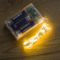 Warm white LED copper wire string lights with clear battery box on dark wooden table - 3m Copper Wire Flash Battery Warm Yellow
