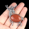 Vintage silver elk brooch pendant with oval reddish-brown goldstone inlay held by hand - Gold Sand Stone (Synthetic)
