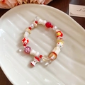 Detail view of colorful ceramic beads and apple core pendant on a white ceramic tray - Red and White Apple Style