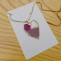 Dettaglio ravvicinato di una collana con ciondolo a cuore dorato con inserti in resina viola - Cuore
