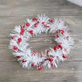 Close-up of white pine needle wreath with red berries and snow effect on wood floor - Snow Flocked Red Berry White Pine Wreath