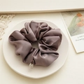 Detailansicht eines Premium-Satin-Scrunchies mit Metallanhänger und edler Plissee-Struktur - Grauviolett