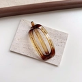 Macro detail of amber tortoise shell resin hair clip showing internal grip teeth and texture - Oval Amber