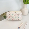 Detailaufnahme der gesteppten Kosmetiktasche mit Blumenmuster und süßen Tiergrafiken - Spitzengebäck