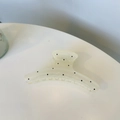 Close-up of translucent yellow hair claw clip with black polka dots on white surface - White Square Hanger