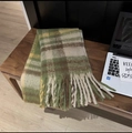 Detail of a thick plaid scarf with long tassels on a table next to a laptop - Baba Plaid Military Green
