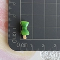 Vista dettagliata di un mini fiocco in resina verde per miniatura con righello di misura - Spiedino di alghe