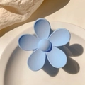 Detailed view of a matte light blue flower-shaped hair claw clip on a white ceramic plate - Sky Blue