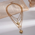 Detailansicht der goldene mehrlagige Kette mit Herzanhängern und Weltkarten-Motiv auf Vintage - Gold