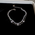 Detail of silver double-layer bracelet with sparkling zircon leaves on black background - Silver