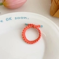 Elastic wavy hair ties in bright orange with blue accents on a decorative plate - Orange