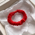 Detail of red velvet scrunchie showing plush fabric texture and matching fastener - Burgundy