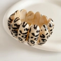 Close-up of wide leopard print acetate bracelet on a white ceramic plate background - Off White