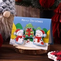 3D pop-up Christmas card featuring cute snowmen holding a gift box on a wooden base - Snowman