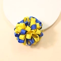 Detailed close-up of blue and yellow ribbed grosgrain ribbon bow on a soft white plate - Yellow and Blue