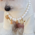 Macro detail of pet pearl necklace with gold heart, Eiffel Tower and crown charms - Heart Tower Crown Pearl Necklace