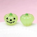 Close-up of light green glowing pumpkin charms with carved smiles on a white plate - Luminous Light Green (Black Expression)