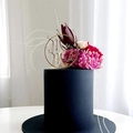 Close-up of golden Mr & Mrs acrylic cake topper on elegant black floral cake - Gold Round Hollow Style MR&MRS