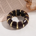 Détail d'un bracelet vintage en acrylique avec blocs de résine ambre et séparateurs dorés - café