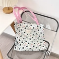Close-up of cute cat print on teal canvas tote bag with pink straps on a chair - Black Cat Dots
