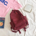 Detailed view of the burgundy minimalist backpack on a white fabric background - Burgundy