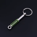 Detail of silver metal car shock absorber keychain with green spring on dark background - Green Shock Absorber