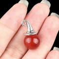 Red agate wizard hat pendant with silver clasp held by fingers against black backdrop - Red Agate