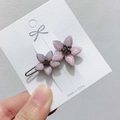 Detail einer lila Blumen-Haarklammer mit Strasssteinen auf weißer Karte - Pink Violett Blume Stil