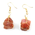 Detail of handmade wire wrapped earrings featuring raw red agate stones with golden finish - Gold + Red Agate