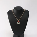 Detail showing a gold necklace with a red bow Christmas wreath pendant on a black bust - Christmas Wreath Style B