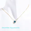 Detailed view of gold necklace with round blue birthstone pendant on white model - December Lake Blue (Blue Topaz/Zircon Color)