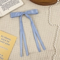 Detail einer hellblauen Haarklammer aus Satin mit Schleife auf elegantem Stoffdekor - Blau