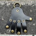 Dettaglio portachiavi in pelle nera a forma di palmo con anello metallico bronzo - Vera pelle nera