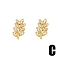 Gros plan de boucles d'oreilles feuilles dorées serties de cristaux de zircon blancs - Lettre C