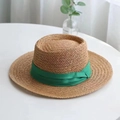 Close-up of a woven straw boater hat featuring a decorative emerald green ribbon bow - 55-58cm Adjustable / Yellow with Green Ribbon