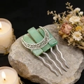 Macro shot of silver crescent moon and green crystals hair comb on a grey stone - Green Aventurine