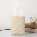 Close-up of beige quilted tote bag with white webbing handles on a lifestyle background - Vertical / Apricot