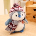 Süßer Plüschpinguin mit rot-grauer Strickmütze und Schal in gemütlichem Ambiente - 12cm Anhänger / Blau