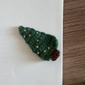 Close-up of a handmade green knitted Christmas tree hair clip on a white paper background - Christmas Tree - Dots