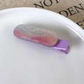 Dettaglio di fermagli in resina rosa e blu con glitter dorati su un piatto bianco - Viola Luccicante