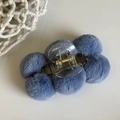 Detail view of a blue plush ball hair claw clip with transparent base on white background - Blue