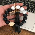 Silicone beaded wristlet keychain with black tassels and marble beads shown held by hand - Black