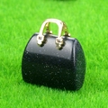 Miniature handbag pendant crafted from dark blue stone with golden handle on green grass - Blue Sand Stone (Synthetic)